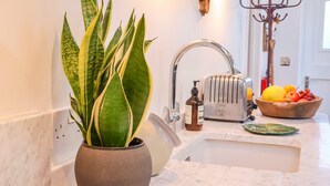 A kitchen with a potted plant, a toaster, and a fruit bowl on the counter. - The Bothy at Snape Hall (Saxmundham)