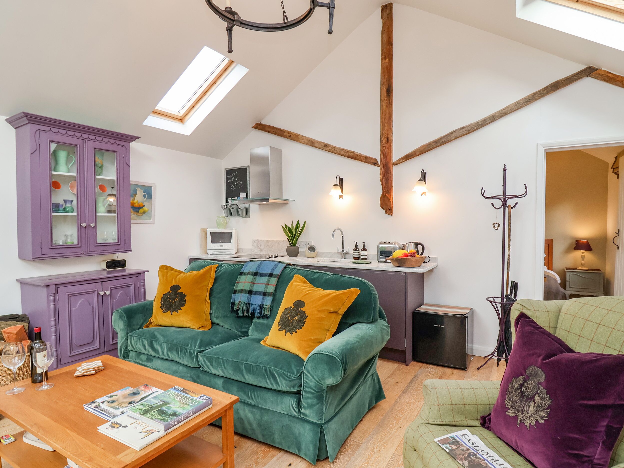 Una sala de estar acogedora con un sofá verde, un mueble morado y una mesa de centro de madera.