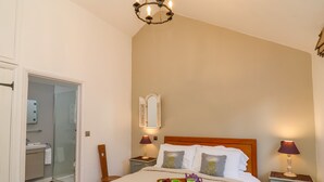 A bedroom with a bed, bedside lamps, a nightstand, a wooden tray with cups and a teapot, and a mirror on the wall. - The Bothy at Snape Hall (Saxmundham)