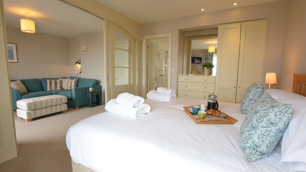 Quarto de hotel com uma cama grande, um sofá, uma cômoda e um espelho.