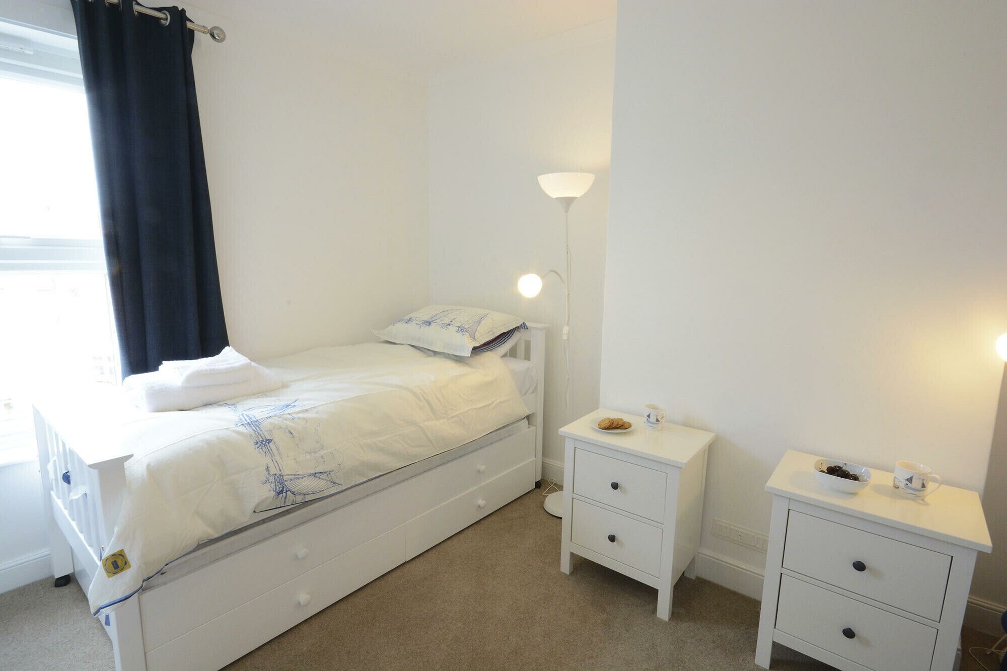 A neatly arranged bedroom with a bed, bedside tables, and a lamp.