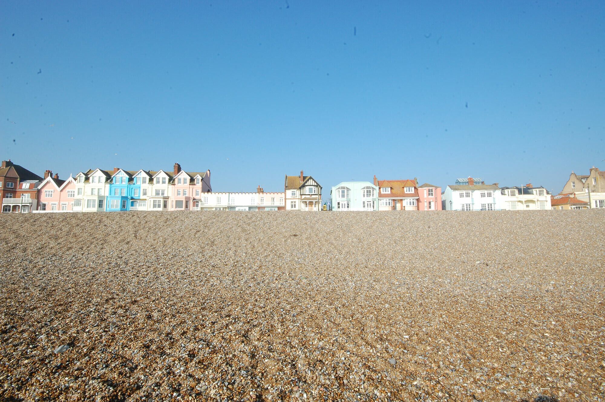 A pebble beach with colorful houses in the background.