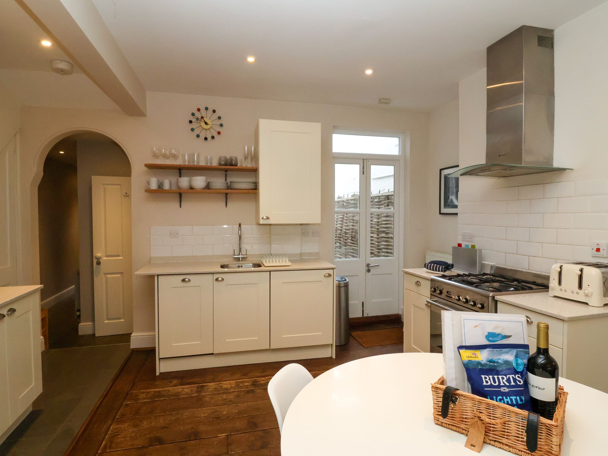 Una cocina moderna con armarios blancos, una campana de acero inoxidable, un horno empotrado y una ventana con vistas al exterior.
