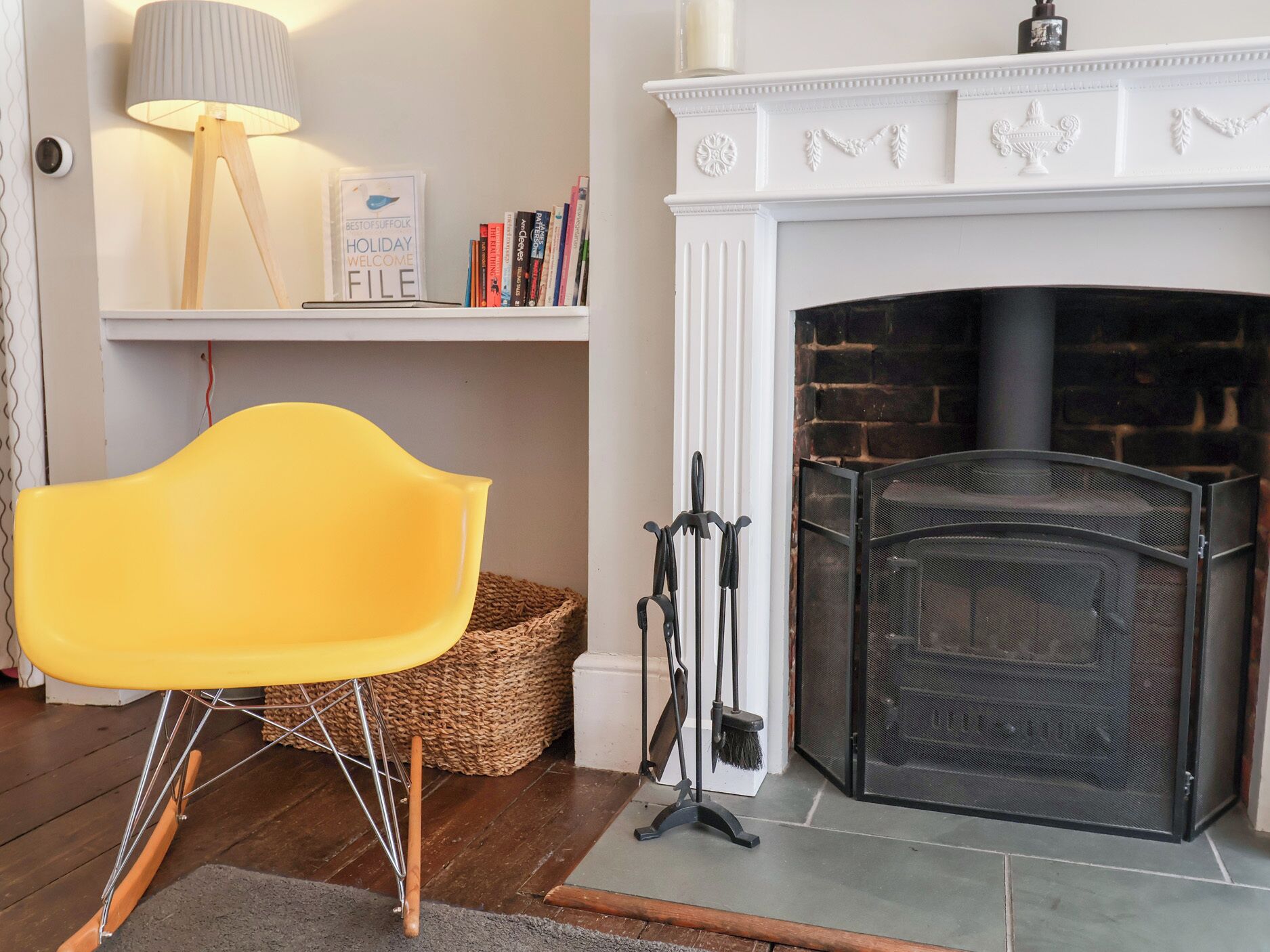 A room with a fireplace, a yellow chair, a lamp, and a bookshelf with books.