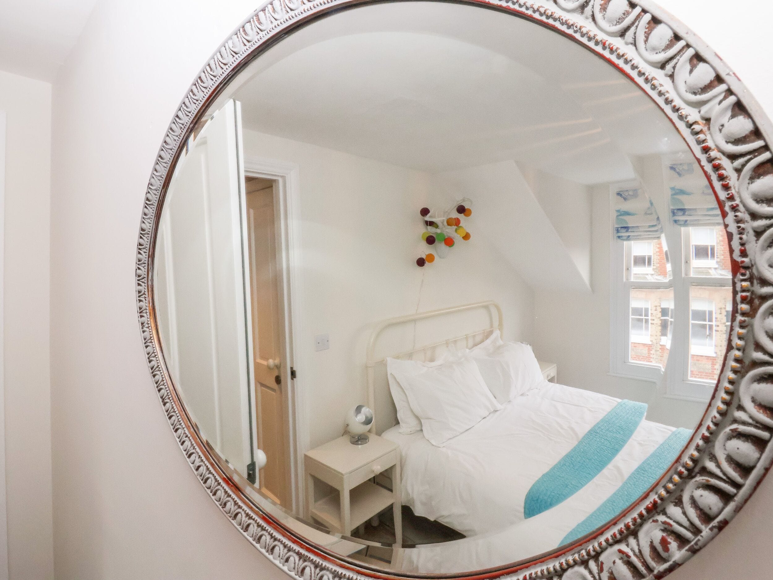 A bedroom with a bed, bedside table, and a mirror.