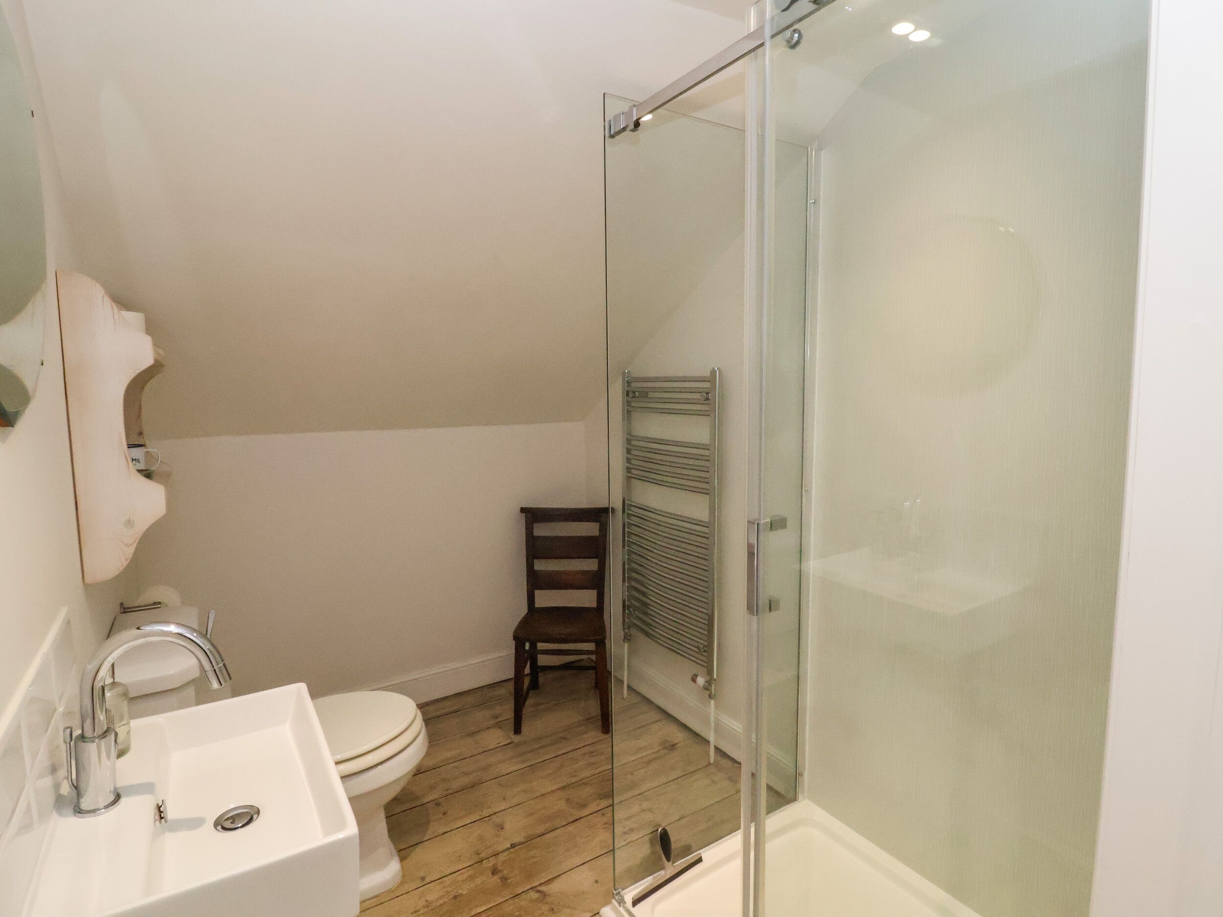 Une salle de bain avec un lavabo blanc, des toilettes et une douche à parois de verre.
