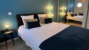 A bedroom with a bed, bedside tables, a mirror, and a ceiling light fixture. - Appartement 6 personnes, 5mn Disneyland Paris, Val d'Europe + Captain America ++ (Chessy)