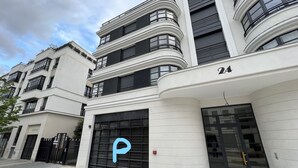 A modern building with a large garage door marked with a 'P' for parking, indicating a parking facility. - Appartement 6 personnes, 5mn Disneyland Paris, Val d'Europe + Captain America ++ (Chessy)