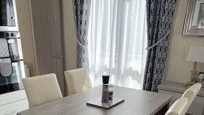 A modern dining area with a rectangular table, four chairs, and a decorative salt and pepper shaker set on the table. - Stunning Lodge in a Nice Area, Saint Leonards (Ringwood)