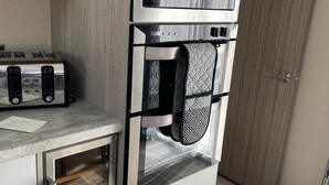 A compact kitchen with a built-in microwave, oven, and toaster. - Stunning Lodge in a Nice Area, Saint Leonards (Ringwood)