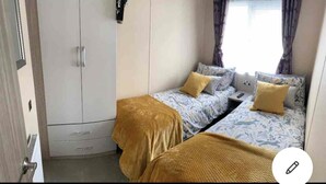A bedroom with two single beds, a wardrobe, and a window with curtains. - Stunning Lodge in a Nice Area, Saint Leonards (Ringwood)