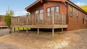 A wooden cabin with a balcony, a satellite dish, and a gravel driveway. - Lodge 9 by Interhome (Kinross)