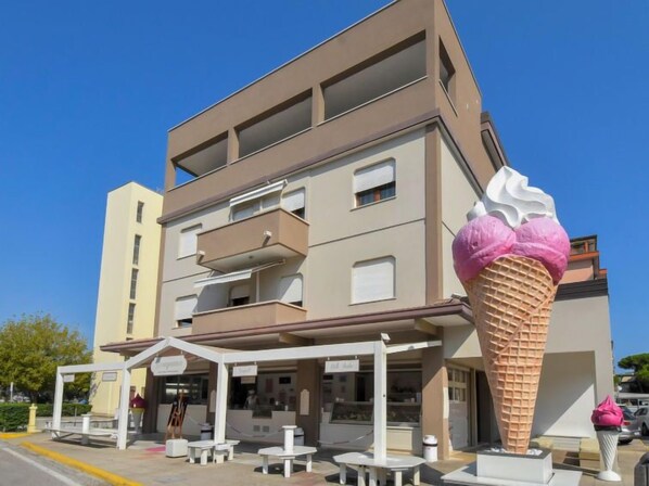 Un bâtiment moderne doté d’un toit plat, de nombreux balcons et d’une grande sculpture en forme de cornet de glace à l’avant.