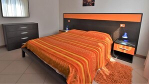 Quarto com cama, mesa de cabeceira, cômoda, espelho e um quadro na parede.