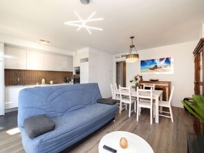 A modern living room with a blue sofa, a dining table with white chairs, and a kitchen in the background. - Isea Calpe by Interhome (Calpe/Calp)