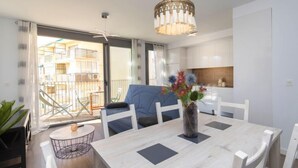 Eine moderne Küche mit weißen Schränken, ein Essbereich mit einem Marmortisch und ein Balkon mit Gartenmöbeln.
