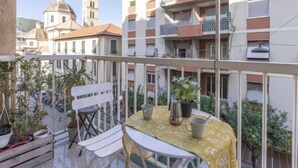 Ein Balkon mit Tisch, Stühlen und Topfpflanzen.