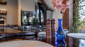 Una encimera de cocina con un florero azul que contiene flores rosas, saleros y pimenteros de madera y individuales tejidos.
