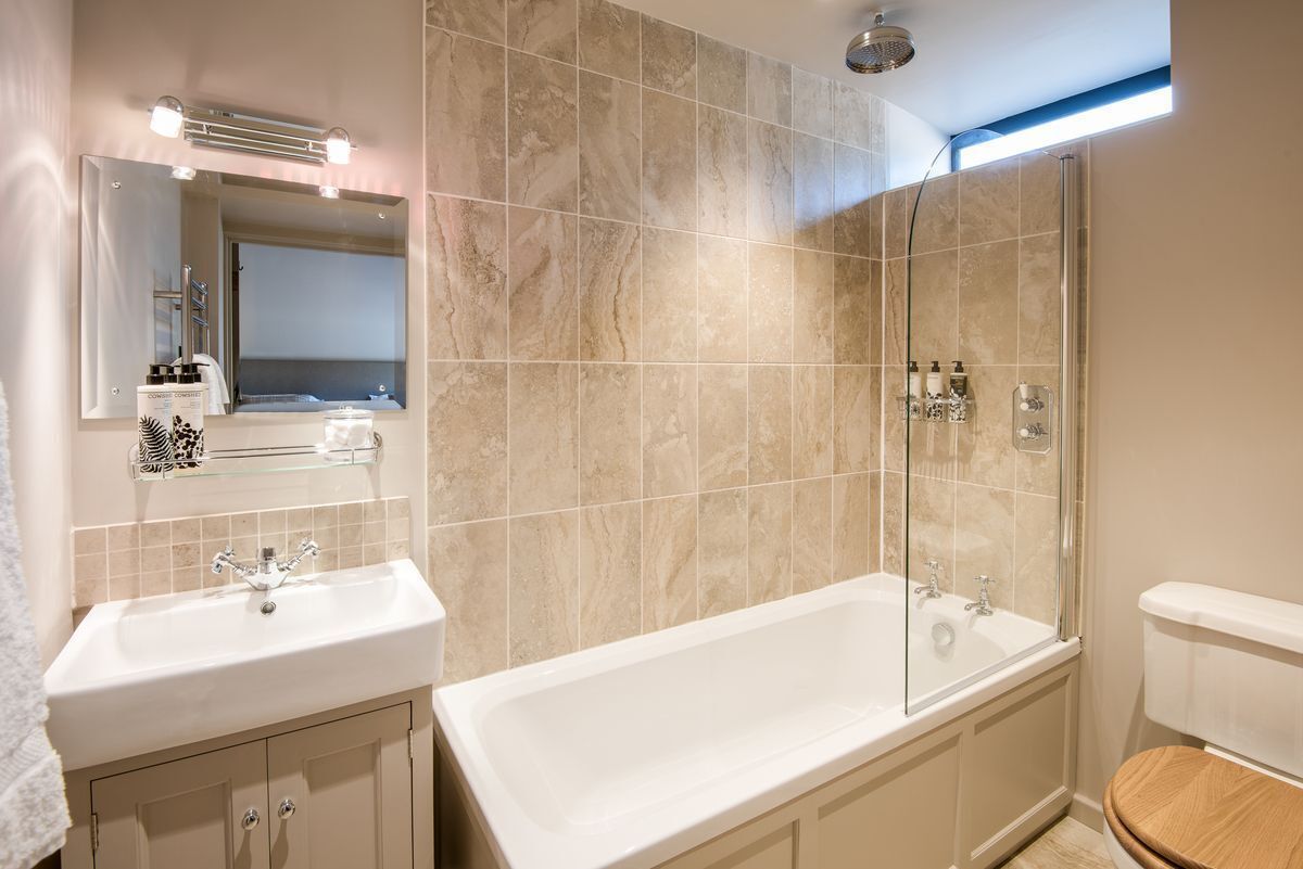 A modern bathroom with a large bathtub, a separate shower area, and a vanity with a mirror and shelves.