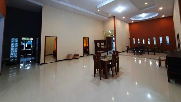 A spacious hotel lobby with a central dining area, multiple seating arrangements, and a large mirror reflecting the space. - 999 KHS 2 Homestay (Banyuwangi)