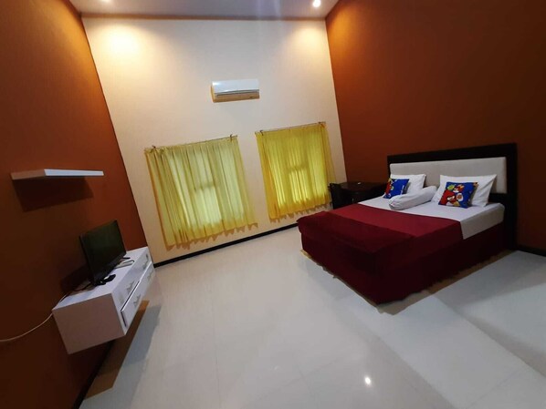 Una habitación de hotel con cama, escritorio y dos ventanas con cortinas.