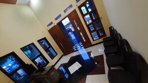 A waiting area with a reception desk, several chairs, and a check-in counter. - 999 KHS 2 Homestay (Banyuwangi)