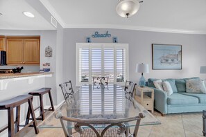 Un coin repas avec une table en verre, des chaises en bois et un canapé bleu dans le salon.