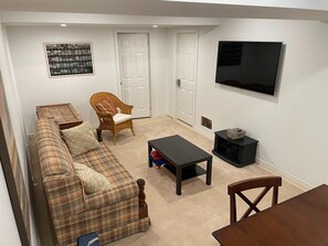 Relax in this cozy living space with a plaid sofa, wicker armchair, and flat-screen TV.