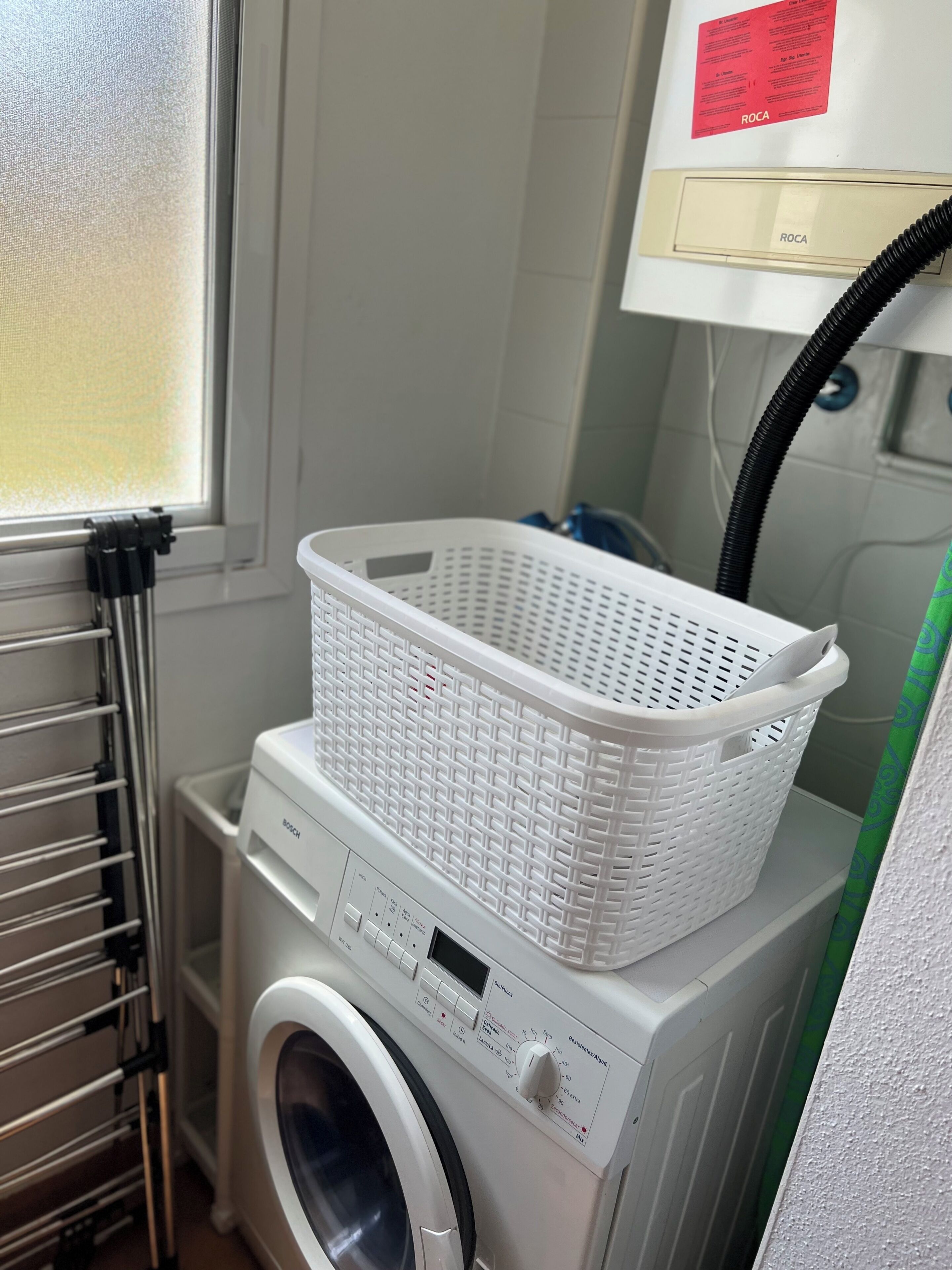 A front-loading washing machine with a white plastic basket on top, a control panel with various buttons and a digital display, and a window with a frosted glass panel.