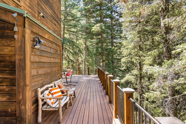 A wooden deck with a railing, benches, and a hammock. - 5 BEDROOM, MOUNTAIN VIEWS, SOUNDS OF STREAM, LARGE DECK, HOT TUB, CLASSIC SUNDANCE CABIN (Sundance)