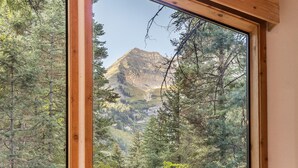 A mountain view through a window framed by wooden beams. - 5 BEDROOM, MOUNTAIN VIEWS, SOUNDS OF STREAM, LARGE DECK, HOT TUB, CLASSIC SUNDANCE CABIN (Sundance)