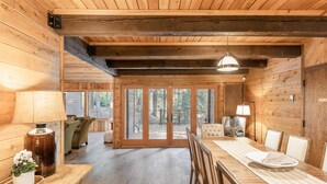A wooden interior with a dining area, a sofa, and a view through glass doors. - 5 BEDROOM, MOUNTAIN VIEWS, SOUNDS OF STREAM, LARGE DECK, HOT TUB, CLASSIC SUNDANCE CABIN (Sundance)