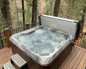 A hot tub on a wooden deck surrounded by trees.