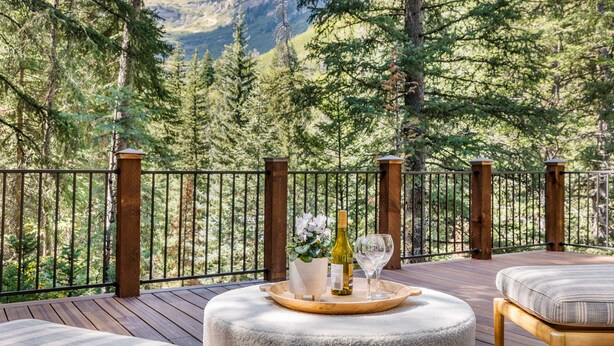A wooden deck with a white cushioned bench and a tray holding a bottle and glass. - 5 BEDROOM, MOUNTAIN VIEWS, SOUNDS OF STREAM, LARGE DECK, HOT TUB, CLASSIC SUNDANCE CABIN (Sundance)