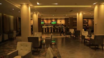A spacious lobby with multiple seating areas, a bar, and a television screen.