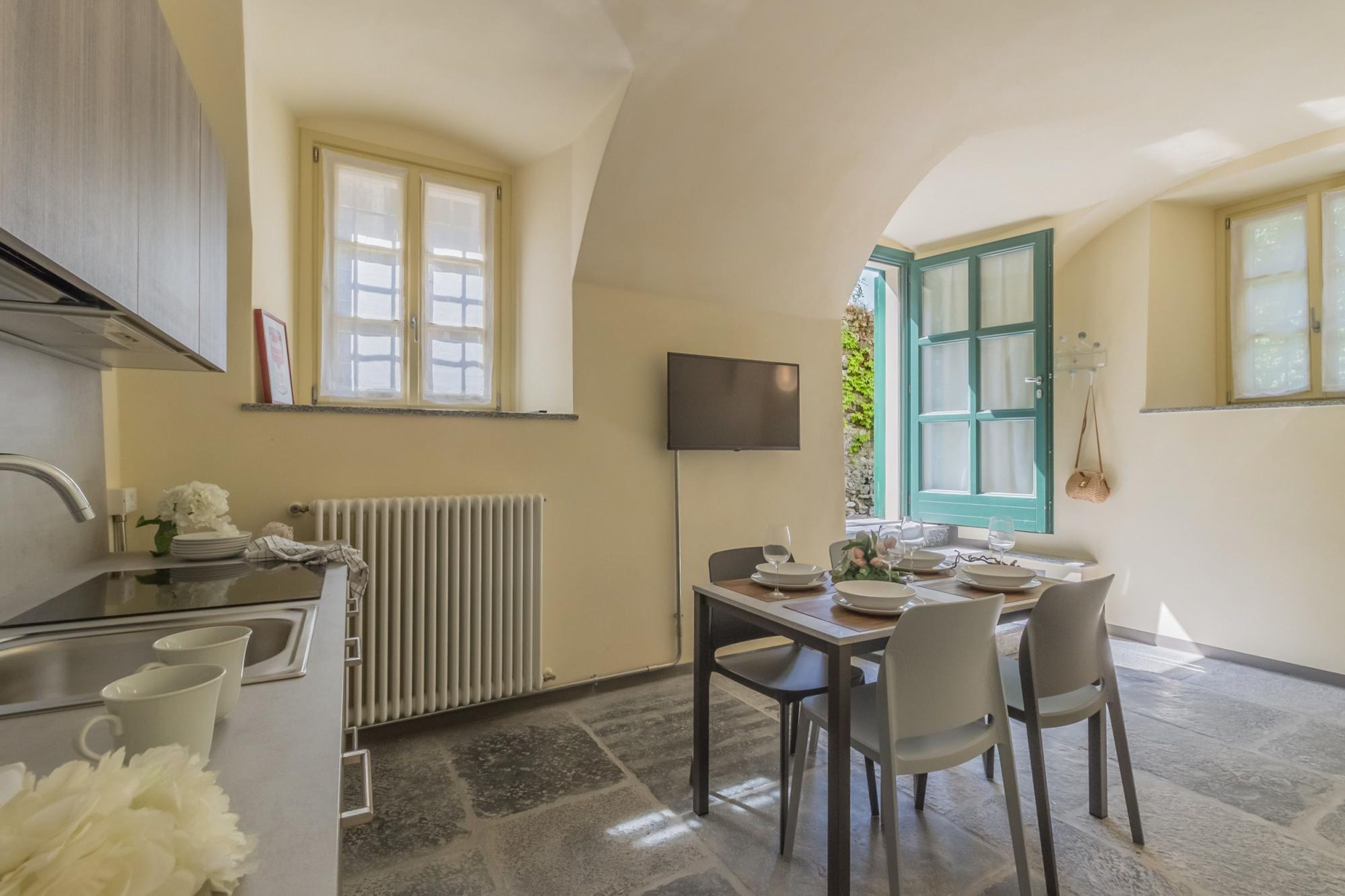 A compact kitchen with a dining area, a radiator, and a TV mounted on the wall.