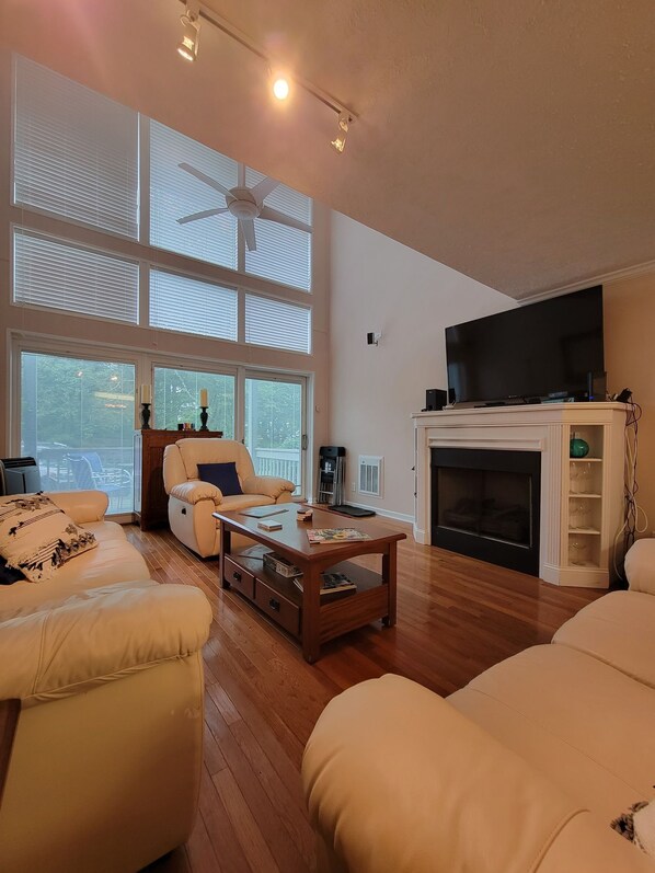 A spacious living room with a fireplace, a television, and a large window with blinds. - Elevation Station...2 story spacious, family friendly condo on Sugar Mountain (Sugar Mountain)