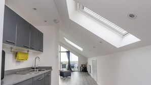 A modern kitchen with grey cabinets, a stainless steel sink, and a skylight. - Sea La Vie (Lytham St. Anne's)