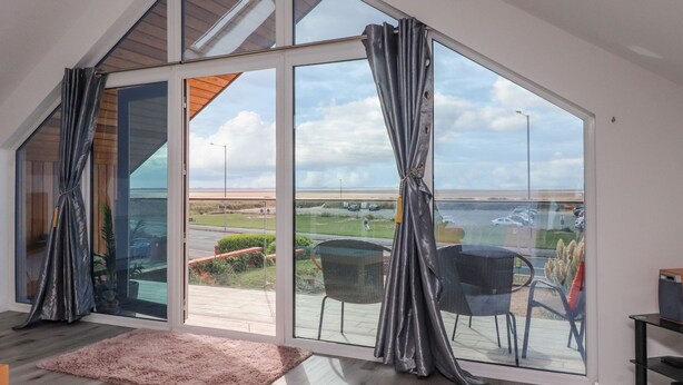 A spacious room with large windows, a view of the outdoors, and a modern interior design. - Sea La Vie (Lytham St. Anne's)