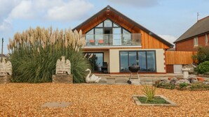 A modern two-story house with a large balcony, a stone statue, and a decorative bird sculpture in the front yard. - Sea La Vie (Lytham St. Anne's)