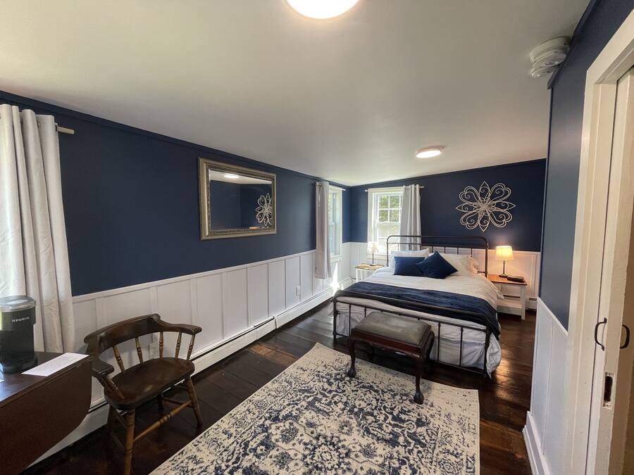 Une chambre à coucher avec un lit, des tables de chevet, une chaise, un tapis et un miroir au mur.