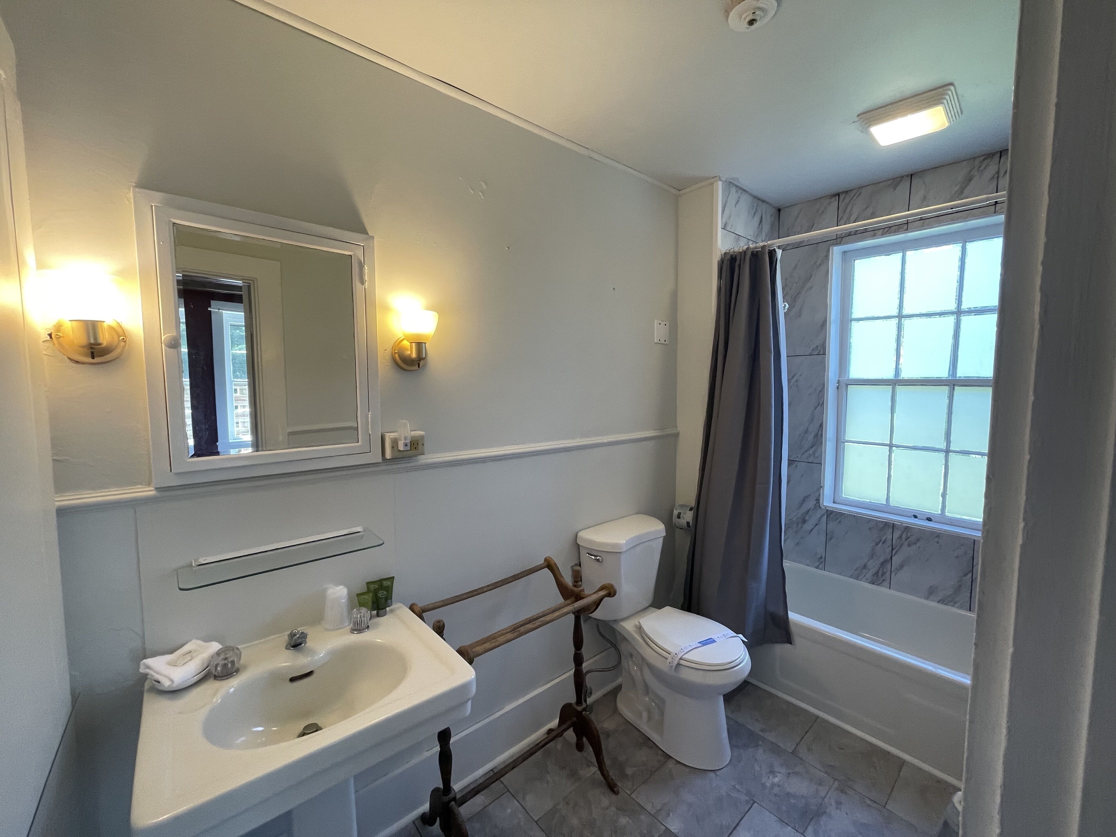 A bathroom with a white sink, a toilet, a mirror, and a shower curtain.