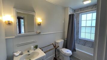 A bathroom with a white sink, a toilet, a mirror, and a shower curtain.