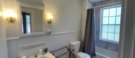Un baño con lavamanos blanco, inodoro, espejo y cortina de ducha.