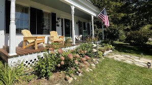 A white house with a porch, wooden chairs, and an American flag. - Stone Hearth Inn and Eatery (Chester)