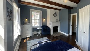 A bedroom with a bed, a fireplace, a window, a dresser, and a clock on the wall. - Stone Hearth Inn and Eatery (Chester)