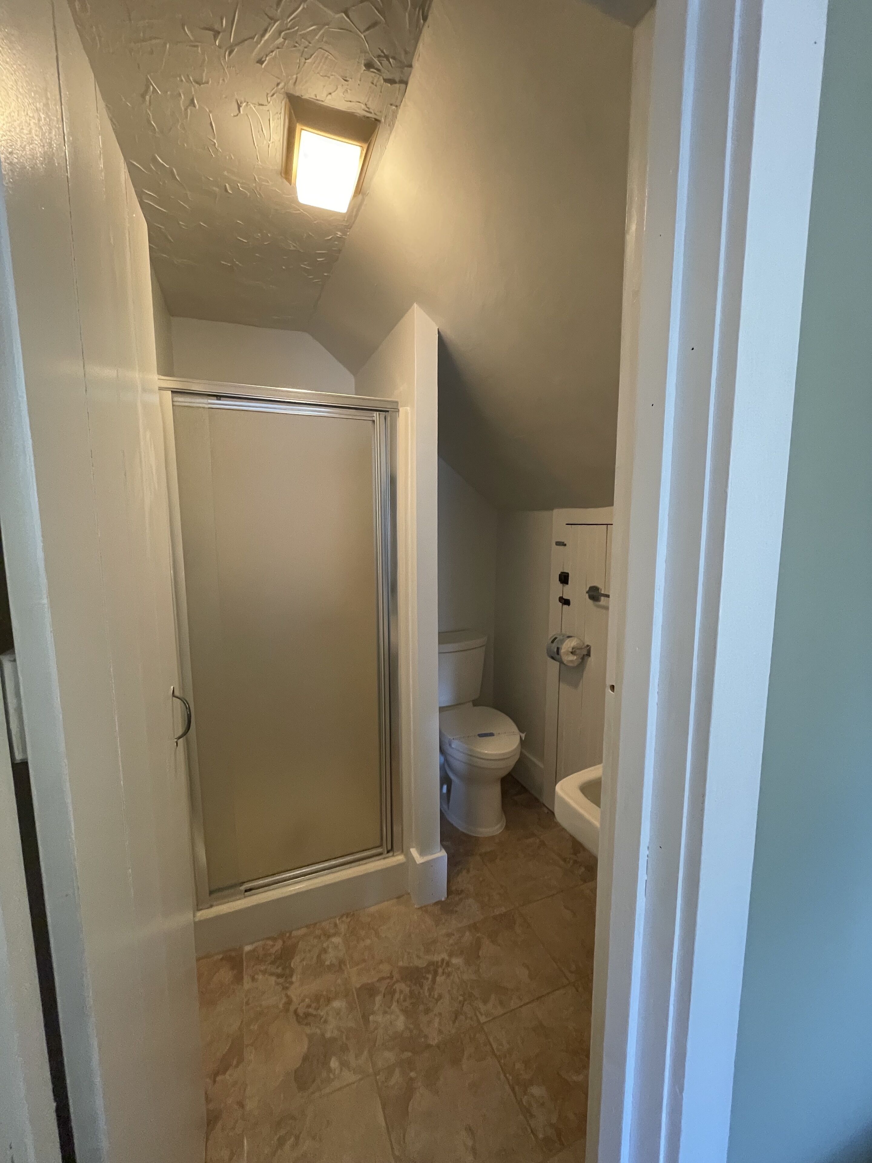 A bathroom with a shower, toilet, and sink.