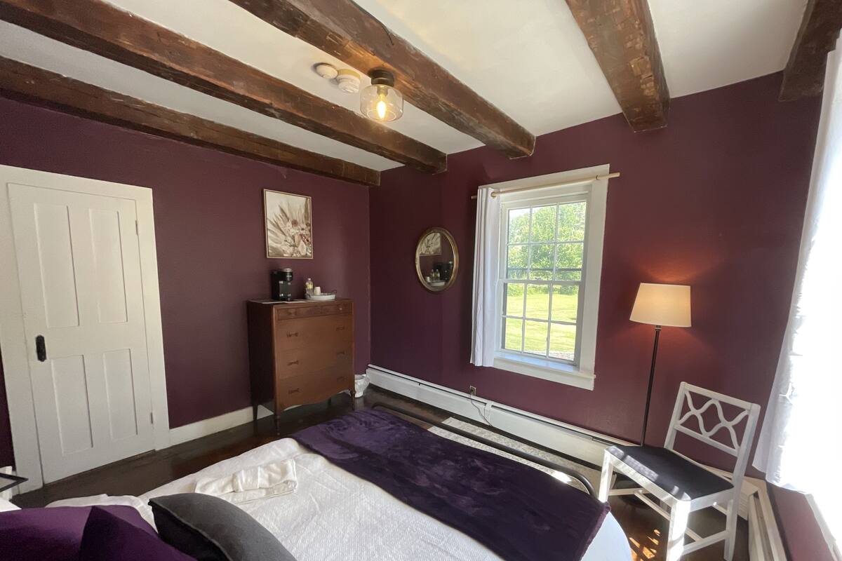 A bedroom with a bed, dresser, window, and a chair.