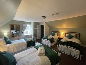 Ein Hotelzimmer mit zwei Einzelbetten, einem Schreibtisch mit Lampe, einem Stuhl und einem großen Fenster.