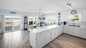 Un'ampia cucina con isola centrale, mobili bianchi, un'ampia finestra e vista sull'esterno.